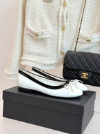 White leather ballet flats with black trim and bow, Chanel