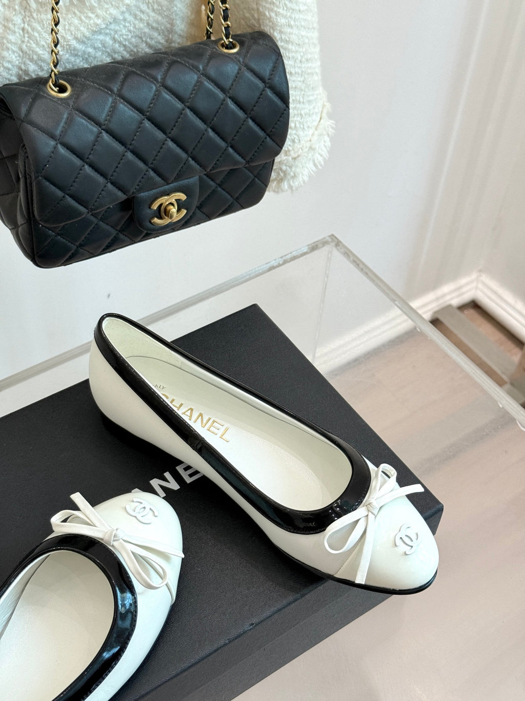 White-and-black ballet flats with bow, on black box