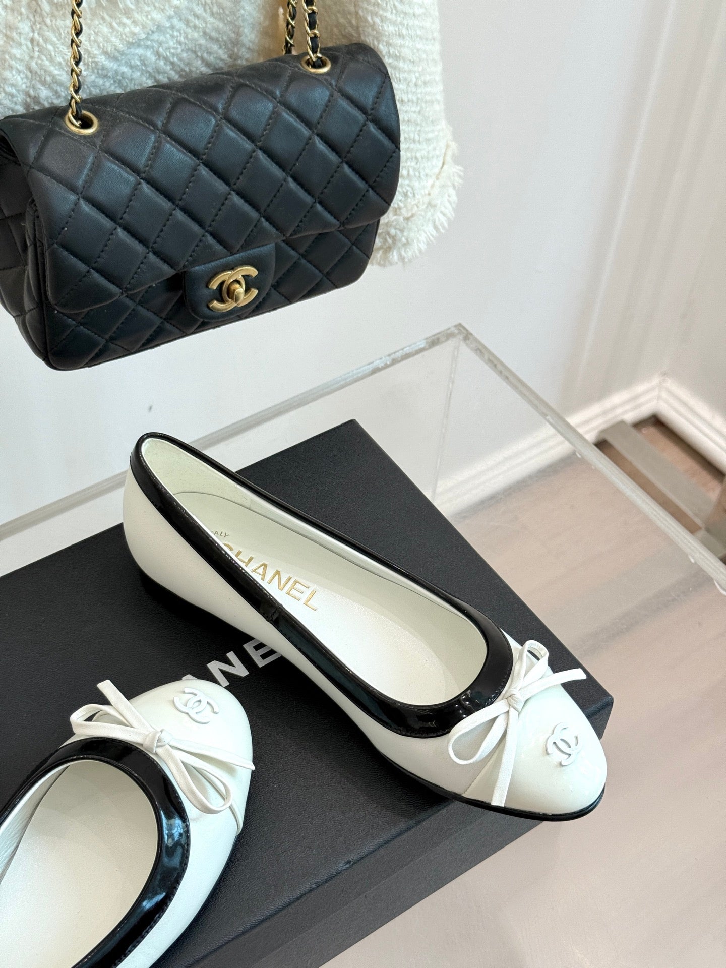 White-and-black ballet flats with bow, on black box