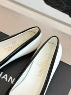 White ballet flats showing gold 'CHANEL' on insole