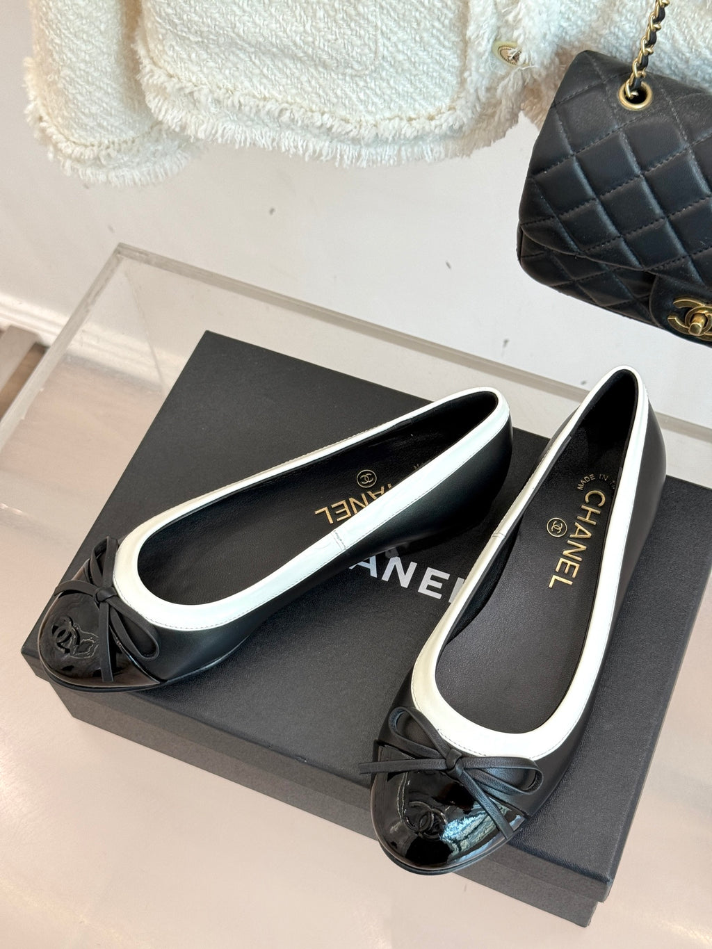 Black ballet flats with white trim and bows, round toe on shoe box