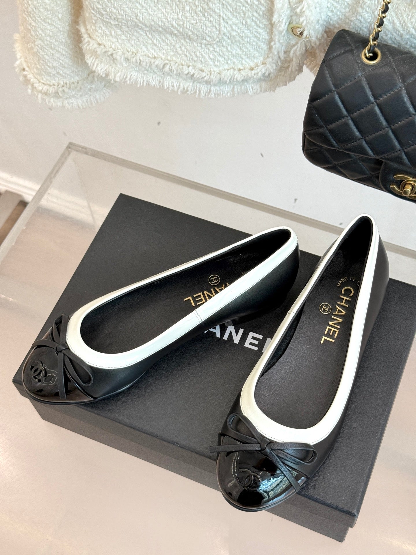 Black ballet flats with white trim and bows, round toe on shoe box