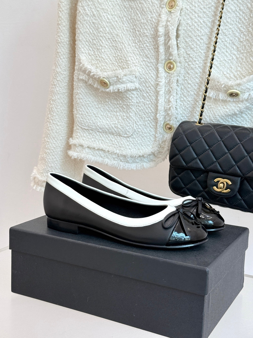 Black leather ballet flats with white edging, round toe and black bow detail