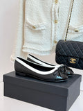 Black leather ballet flats with white edging, round toe and black bow detail