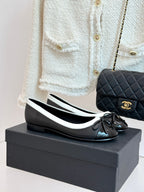 Black leather ballet flats with white edging, round toe and black bow detail