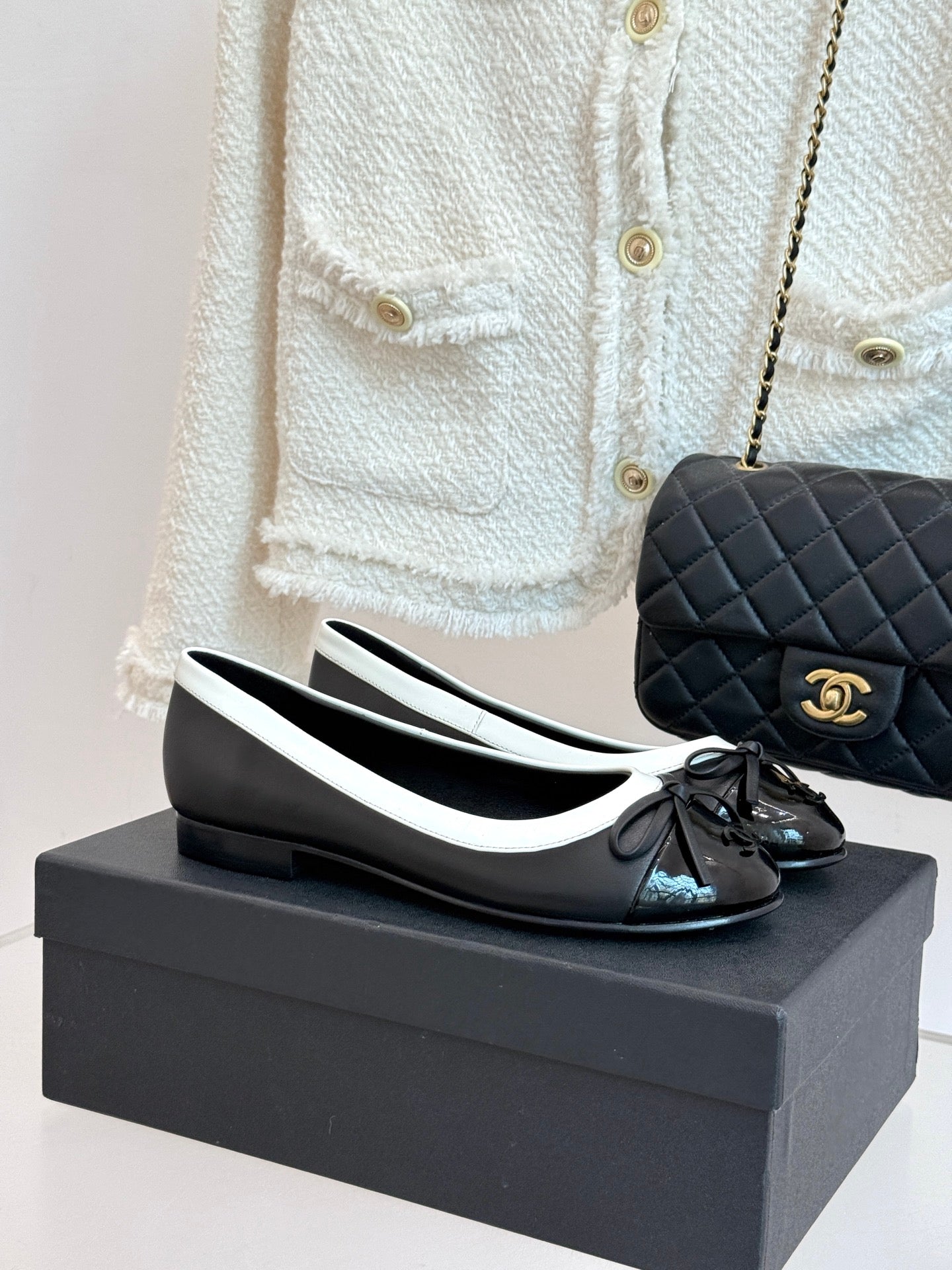 Black leather ballet flats with white edging, round toe and black bow detail