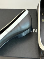 Black leather ballet flat with white trim, rounded toe and low sole close-up
