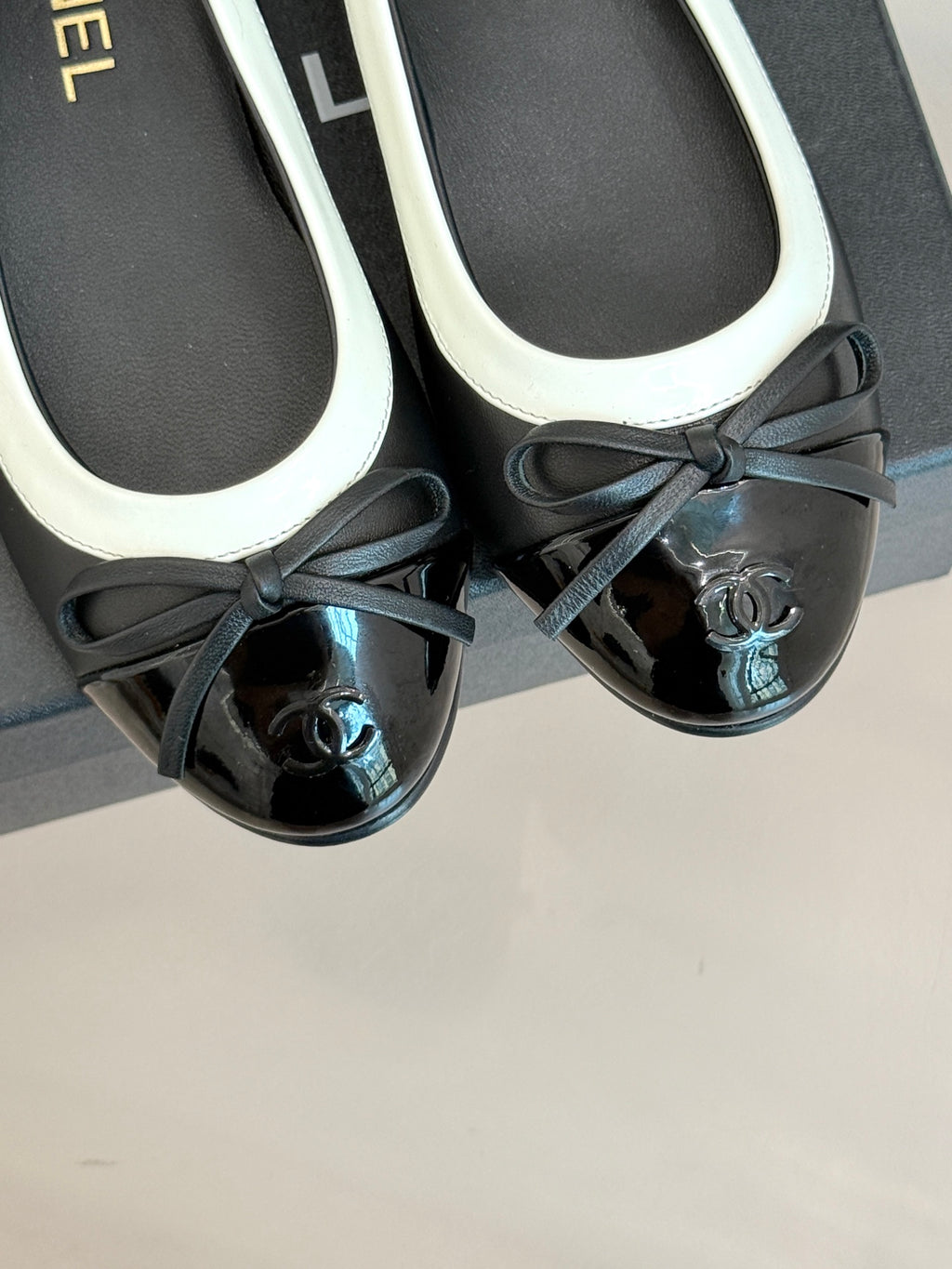 Close-up of black ballet flats with white trim and black bows, round toe