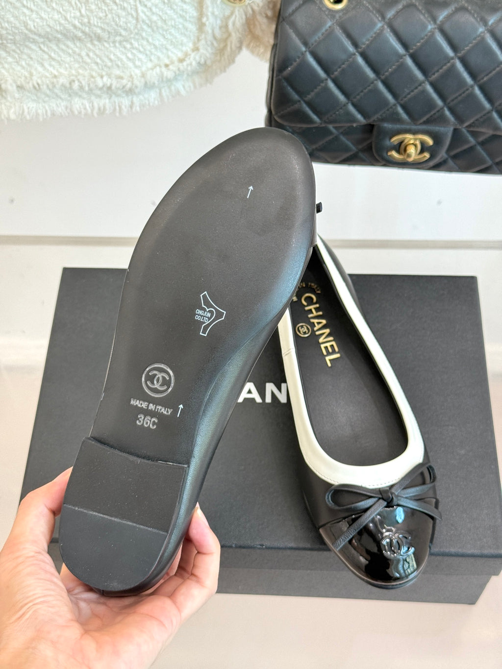 Black ballet flat sole with Chanel logo and white trim, hand holding the outsole