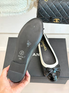 Black ballet flat sole with Chanel logo and white trim, hand holding the outsole