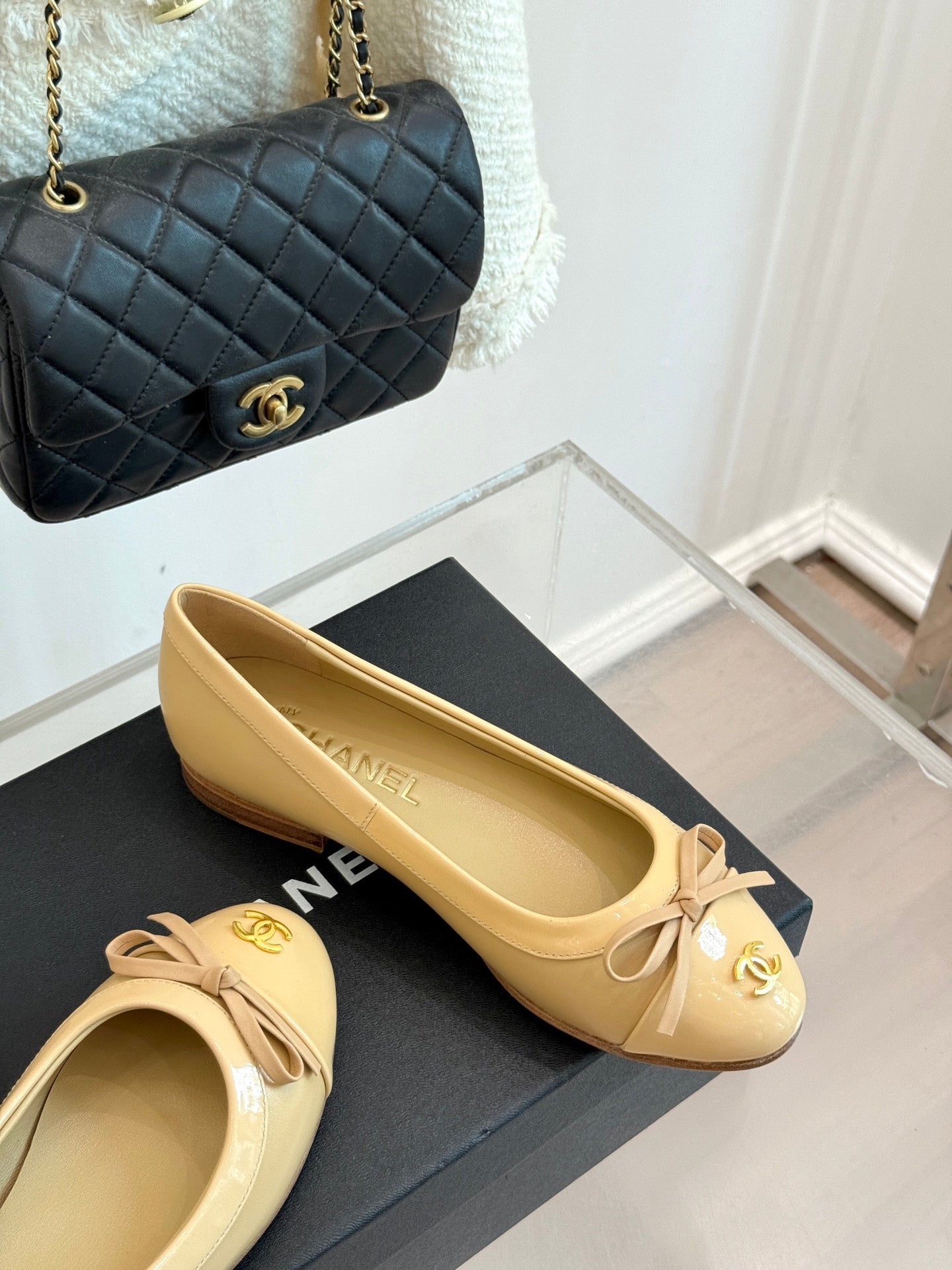 Beige pointed-toe ballet flats with ribbon bows and gold Chanel CC logo