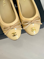 Beige ballet flats with ribbon bows and gold CC logos on toe caps