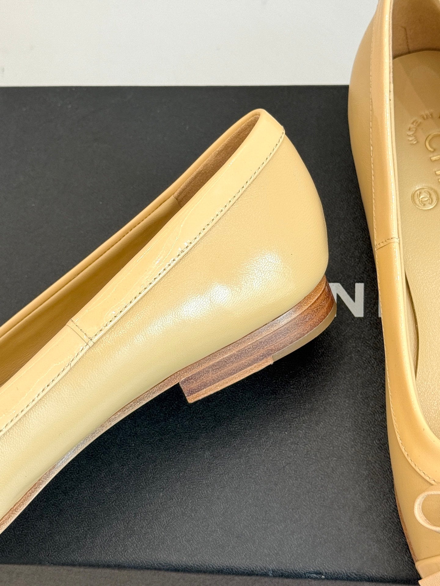 Close-up of beige patent leather ballet flat with decorative edge stitching