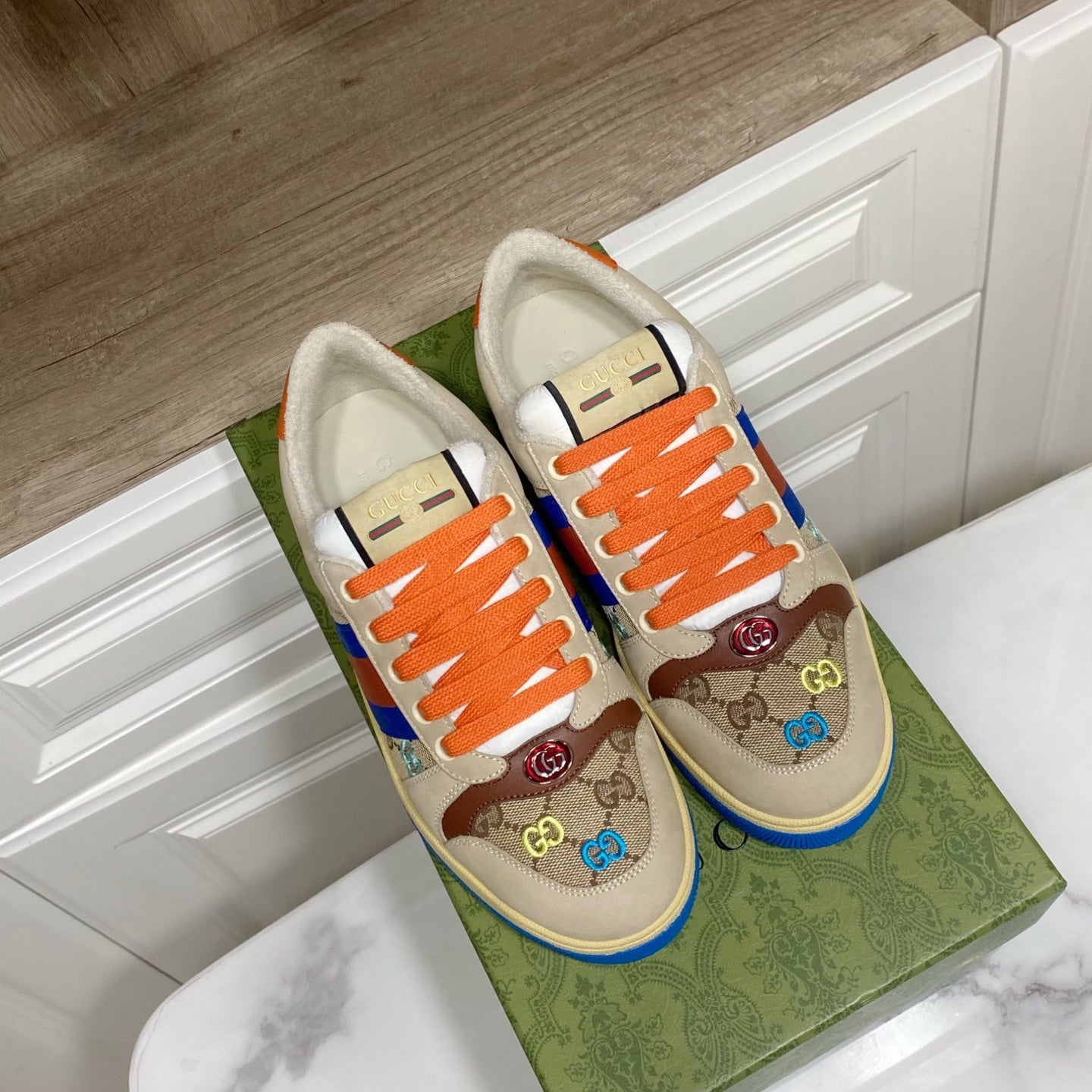 Gucci unisex low-top sneakers, front view with orange laces and blue-red striped panel