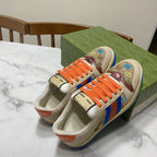 Gucci unisex low-top sneakers, angled pair view with orange laces and multicolor web stripe