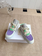 Pair of low-top sneakers with purple toe panel and green lace accents, Dior branding.
