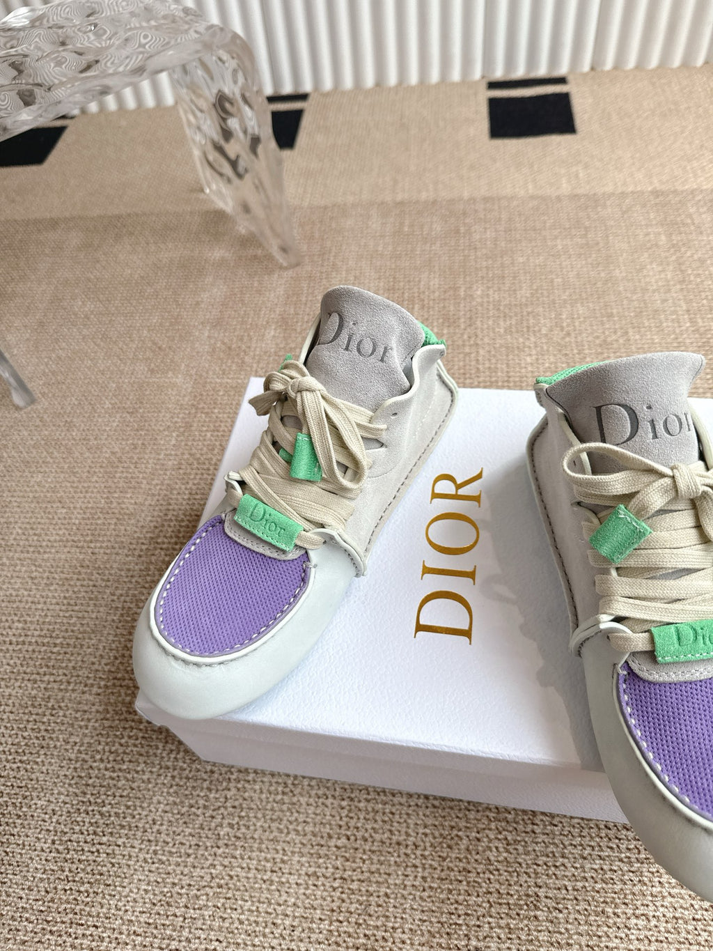 Side angle of low-top sneakers with purple toe panel, green lace accents, Dior on tongue.