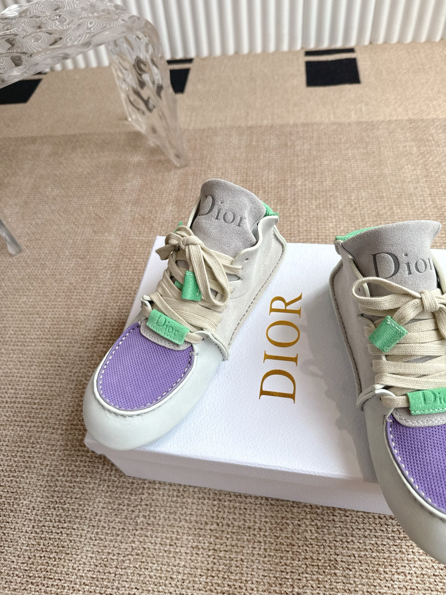 Side angle of low-top sneakers with purple toe panel, green lace accents, Dior on tongue.