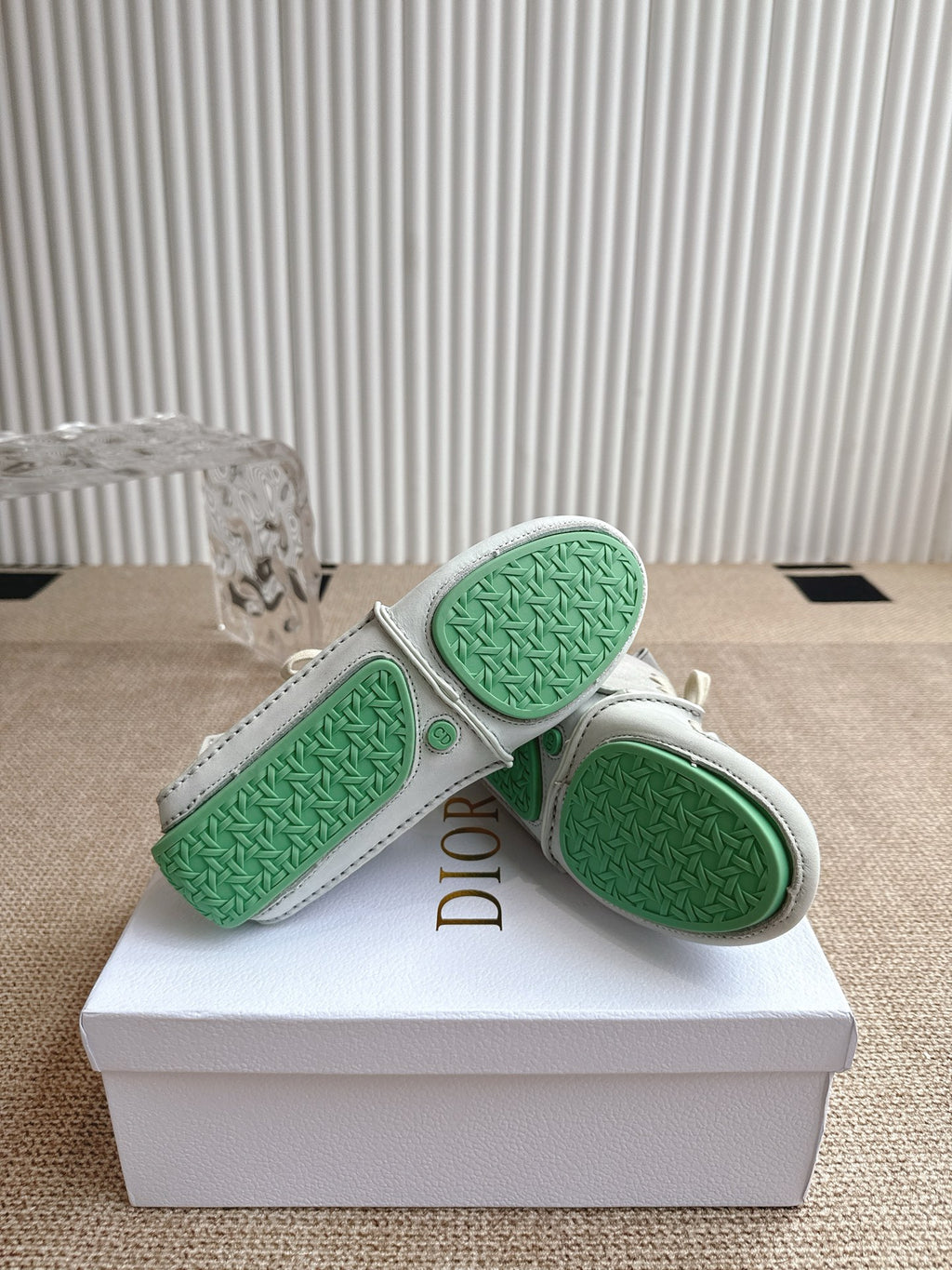 Close-up of sneaker soles with green textured tread and Dior logo on heel.