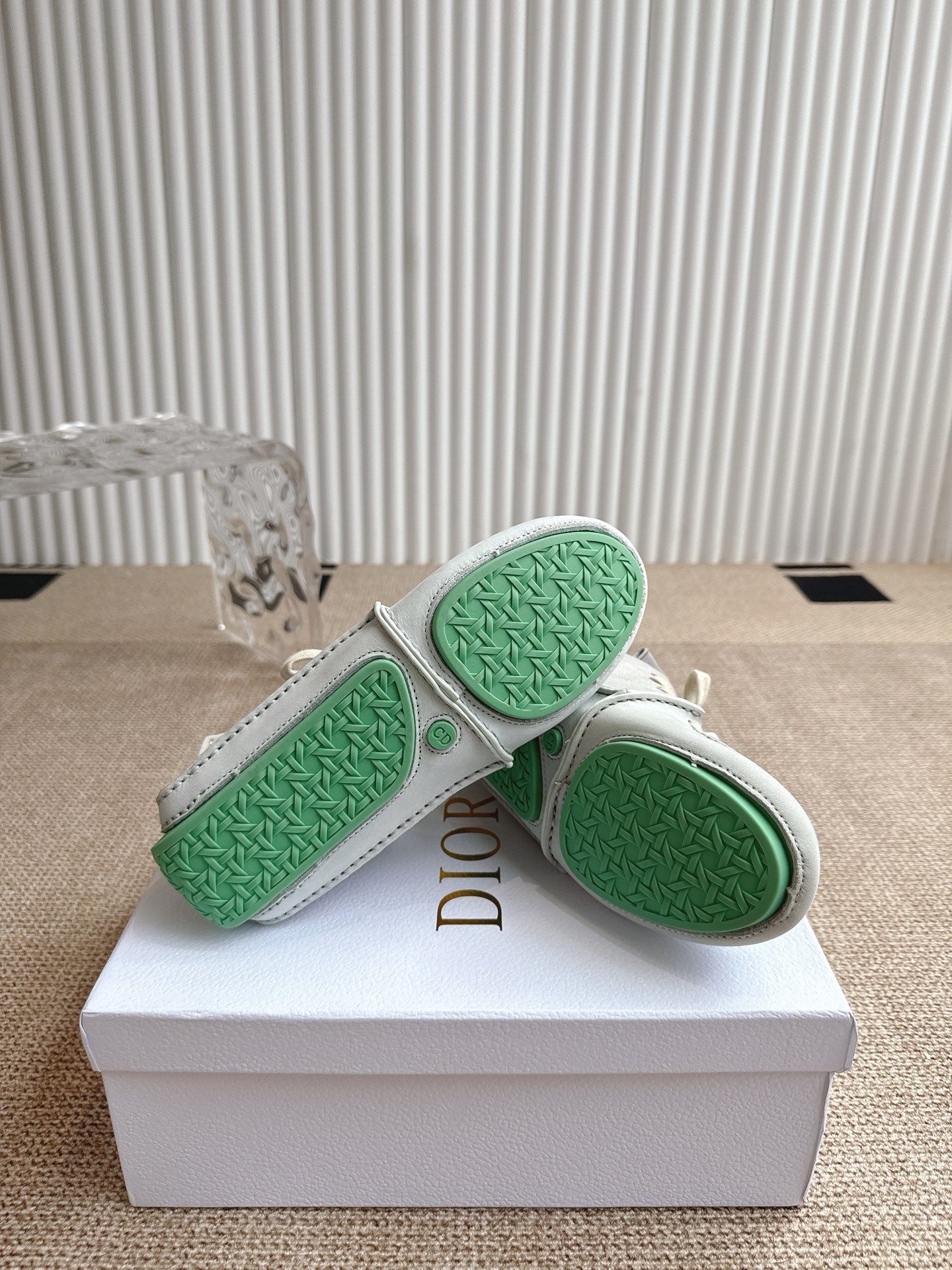 Close-up of sneaker soles with green textured tread and Dior logo on heel.