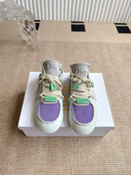 Low-top sneakers on white box: light upper with purple toe and green strap details, Dior.