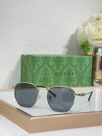 Gucci gold round-frame sunglasses with dark gray lenses and metal temple details
