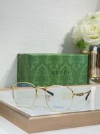 Gucci gold round-frame glasses with clear lenses and GUCCI logo on lens