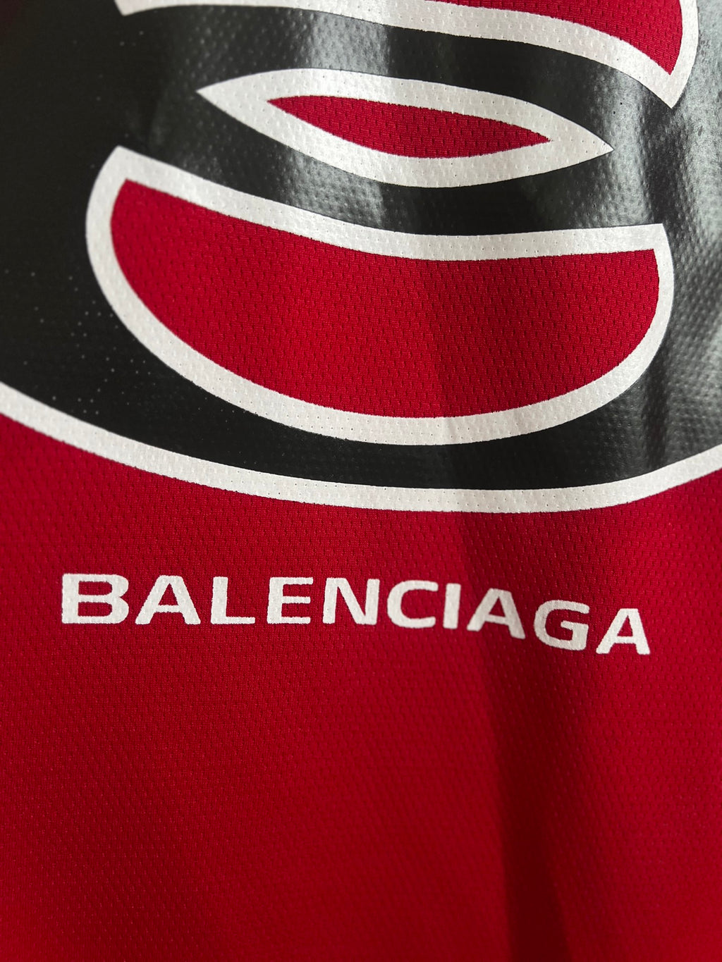 Red jersey chest logo with black-and-white oval graphic and BALENCIAGA lettering