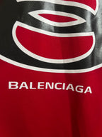 Red jersey chest logo with black-and-white oval graphic and BALENCIAGA lettering