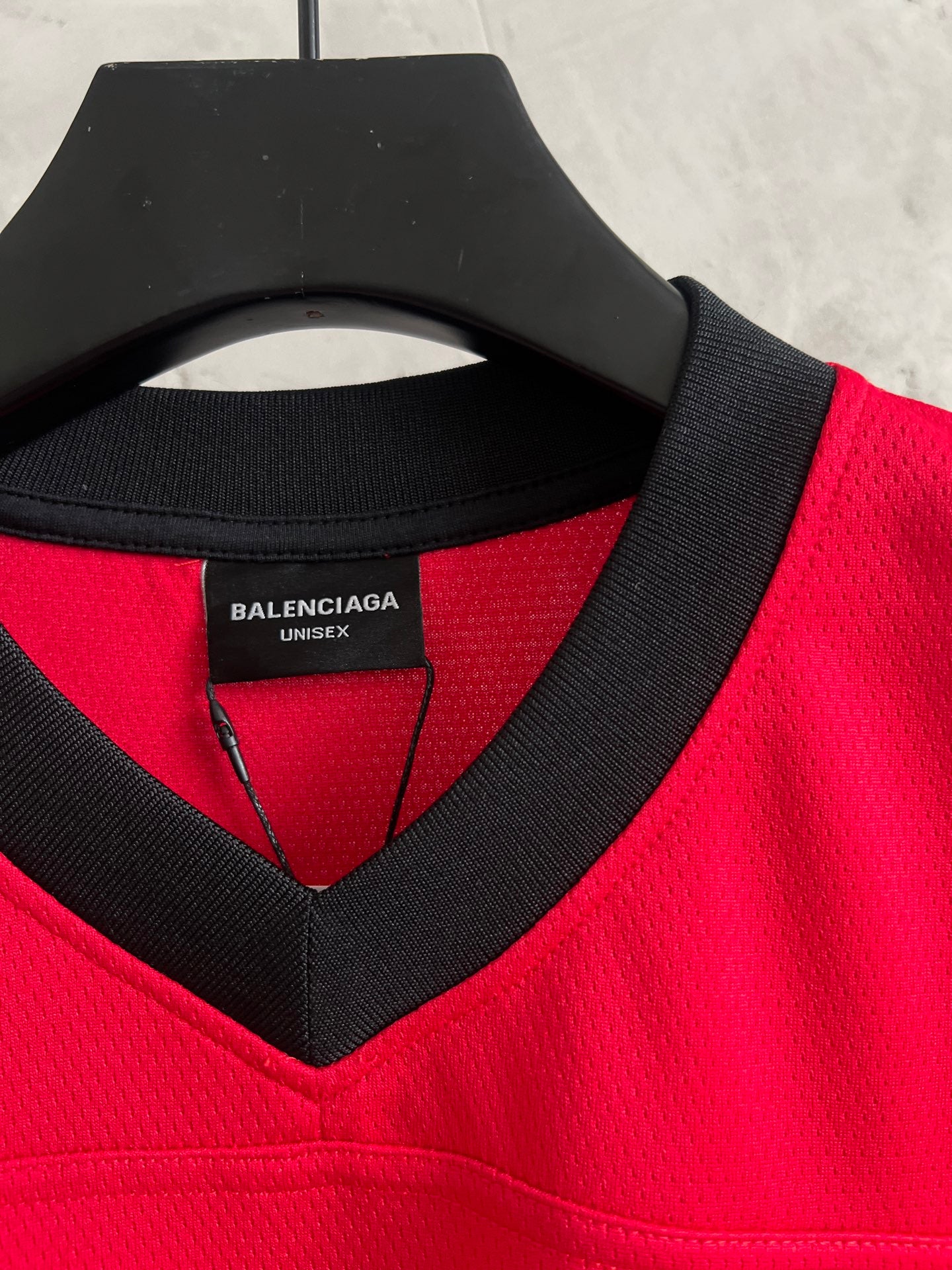 Red jersey close-up of black V-neck label and collar trim under neckline