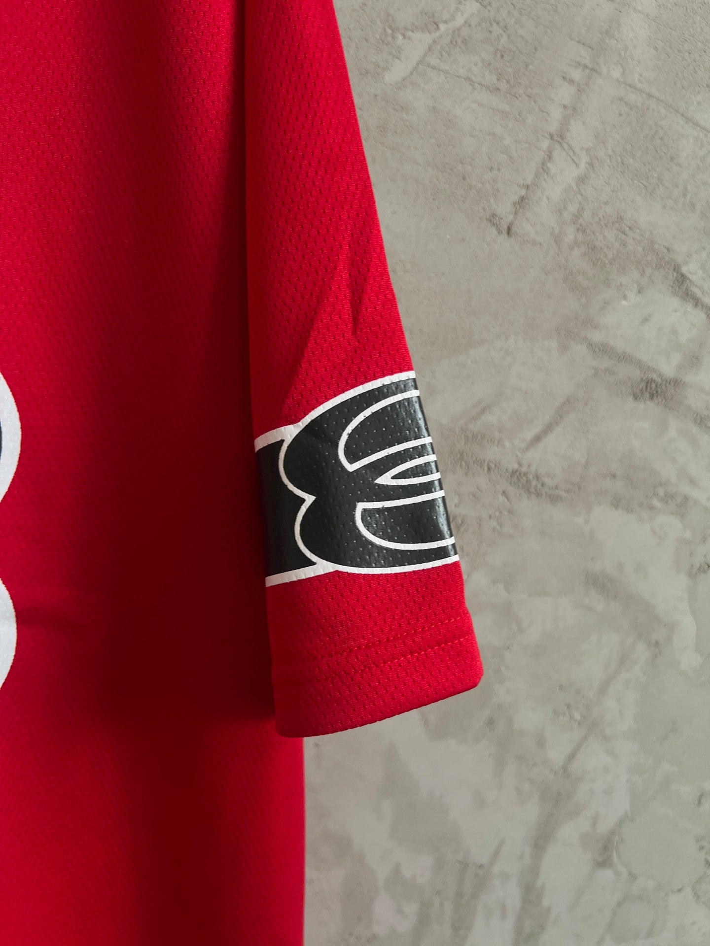 Red short-sleeve sweatshirt with black logo patch on sleeve cuff