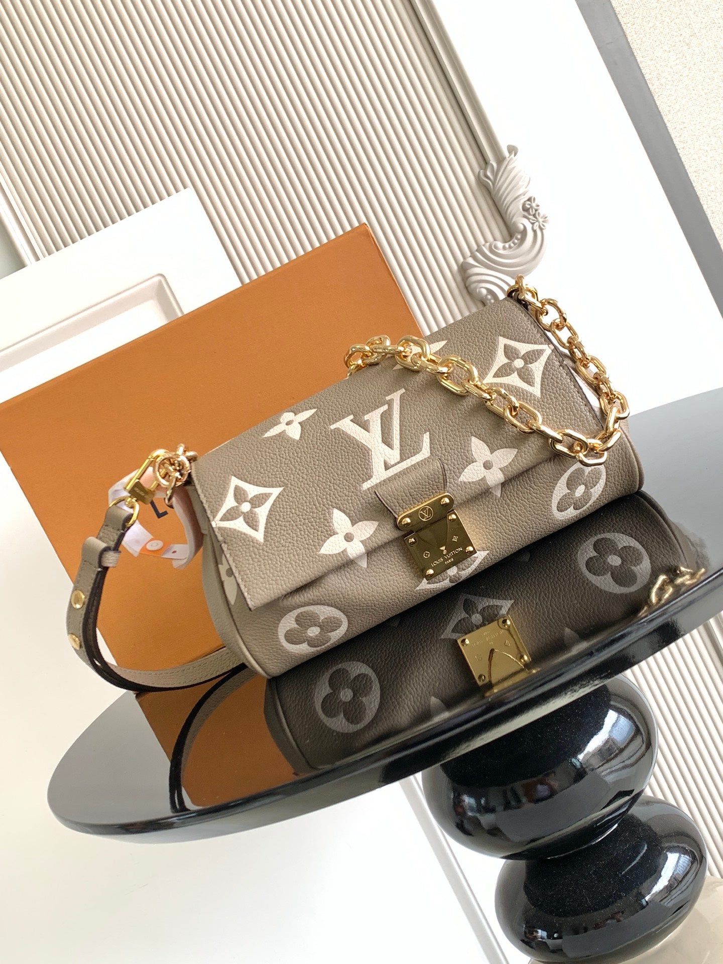 Designer shoulder bag with gray monogram canvas, gold chain strap, flap and clasp.