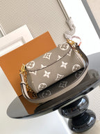 Small flap shoulder bag in gray monogram canvas with gold chain strap and front buckle.