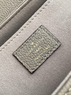 Gray monogram handbag close-up: stitched leather patch with logo on front flap.