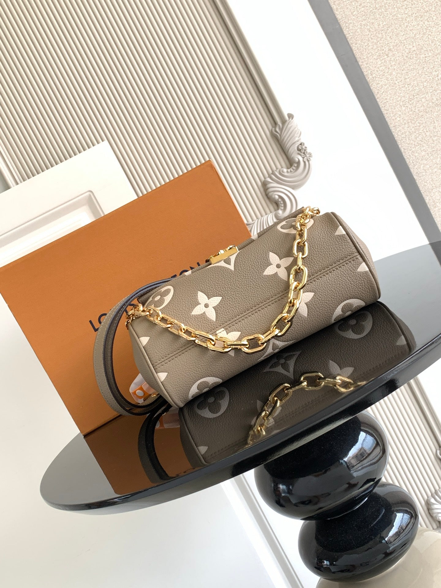 Designer crossbody bag in gray monogram canvas with gold chain strap and flap closure.