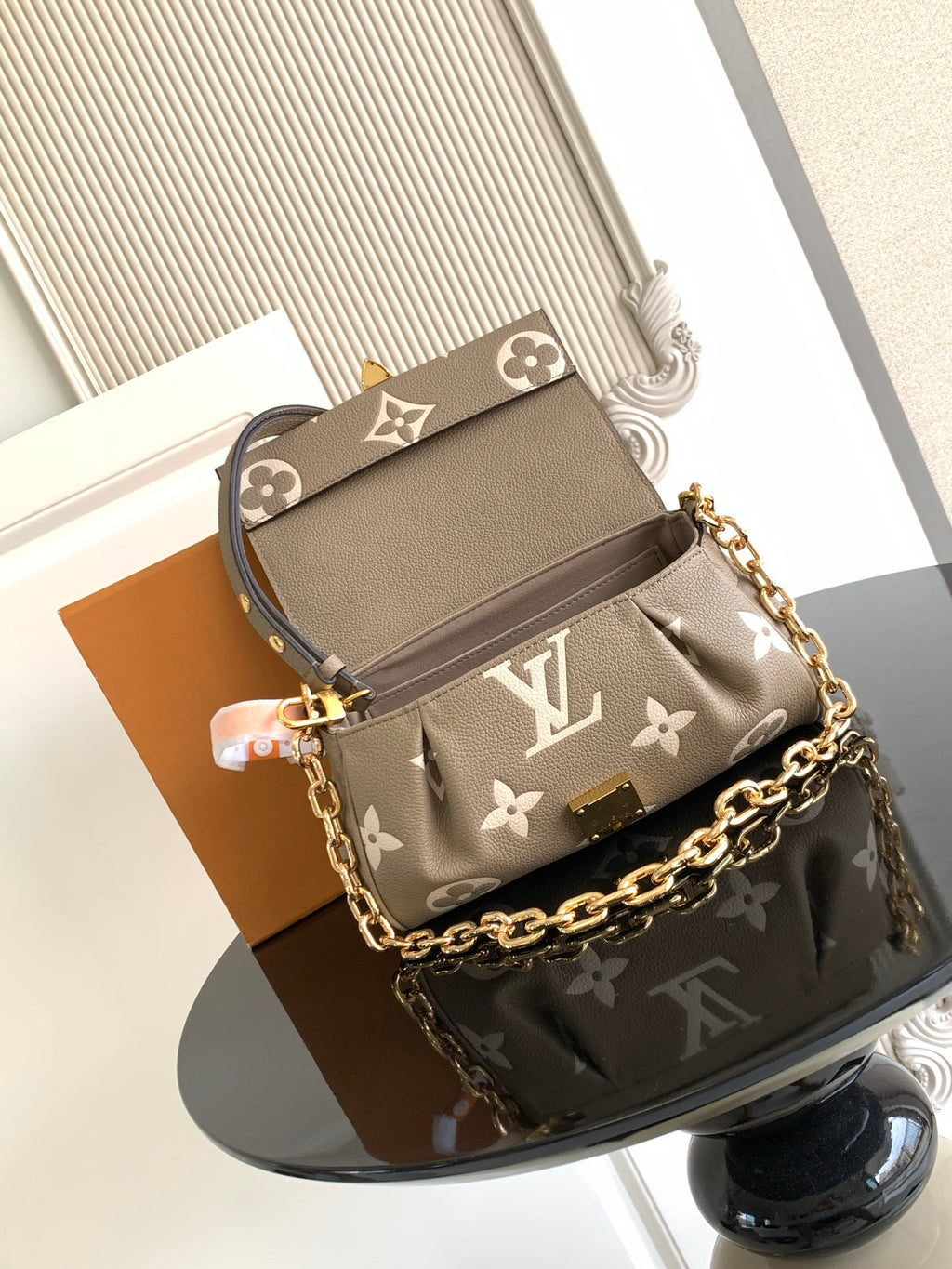 Small designer shoulder bag in gray monogram canvas with gold chain strap and top flap.