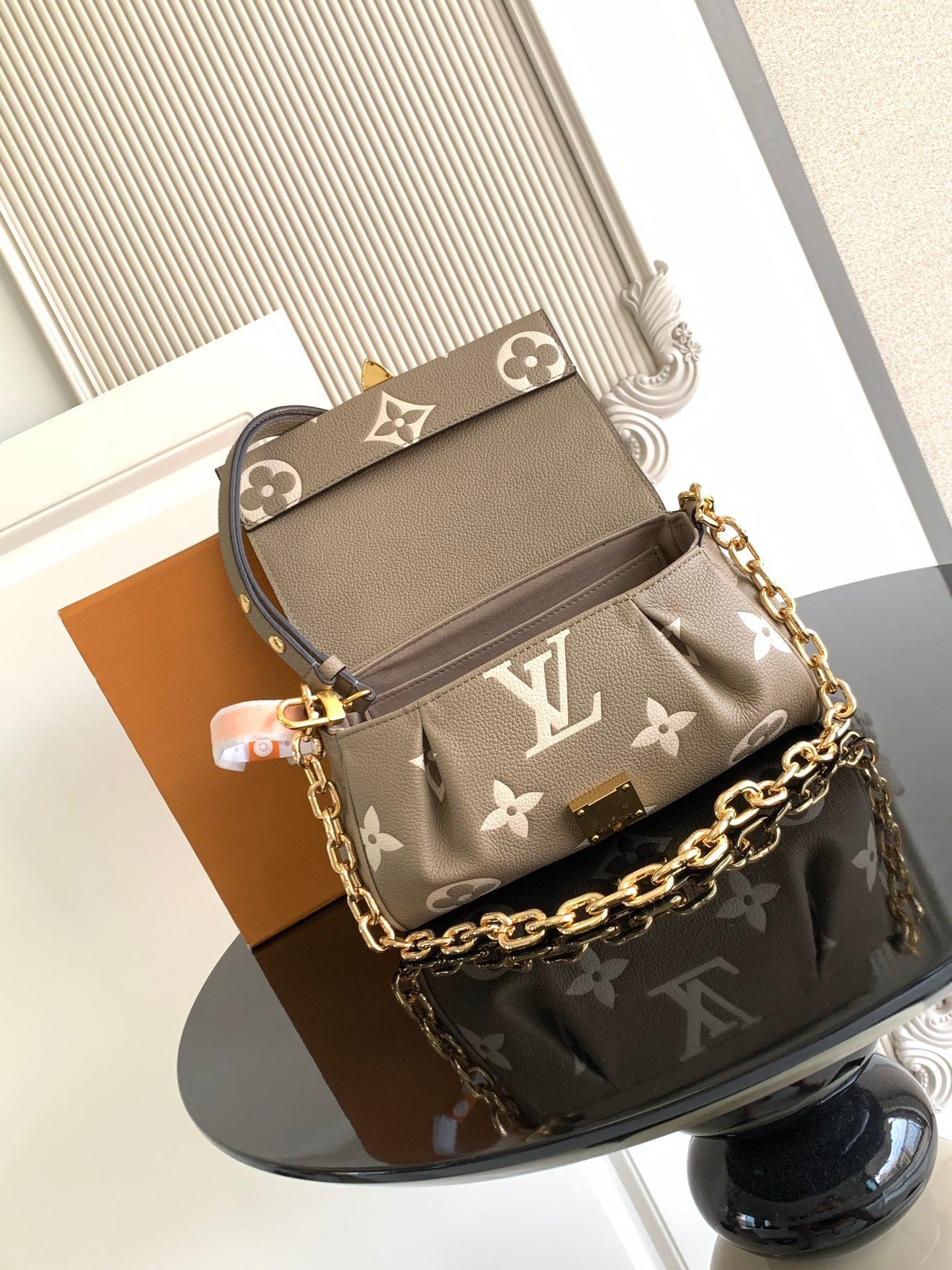 Small designer shoulder bag in gray monogram canvas with gold chain strap and top flap.