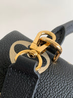 Louis Vuitton monogram bag close-up of gold double-ring clasp on black leather
