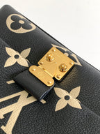 Louis Vuitton monogram bag close-up of gold lockplate and tan floral logos on black