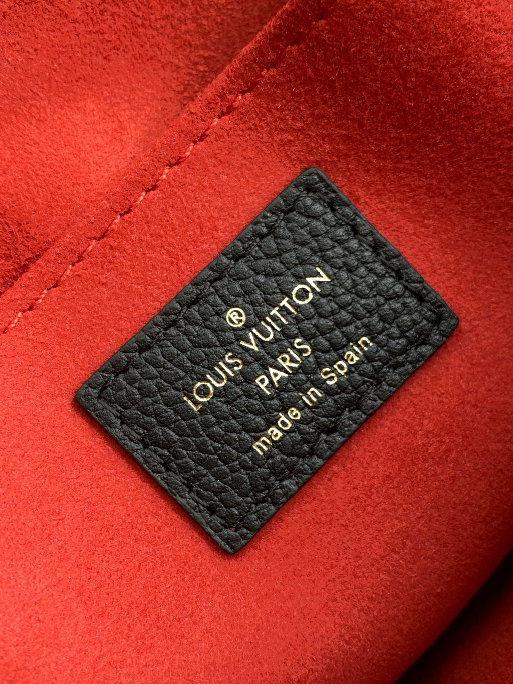 Louis Vuitton label on monogram bag lining, black tag on red fabric