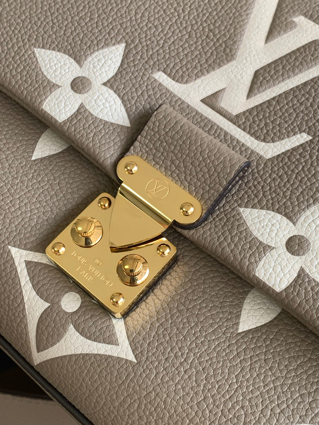 Gold clasp and hardware detail on beige Louis Vuitton monogram bag