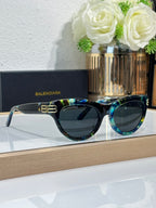 Balenciaga sunglasses with teal-blue frame and dark lenses, gold BB logo on bridge