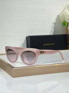 Balenciaga sunglasses with blush pink frame and light lenses, gold BB emblem on bridge