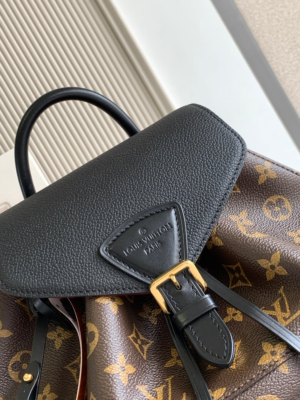 Louis Vuitton monogram bag close-up of black leather flap and gold buckle