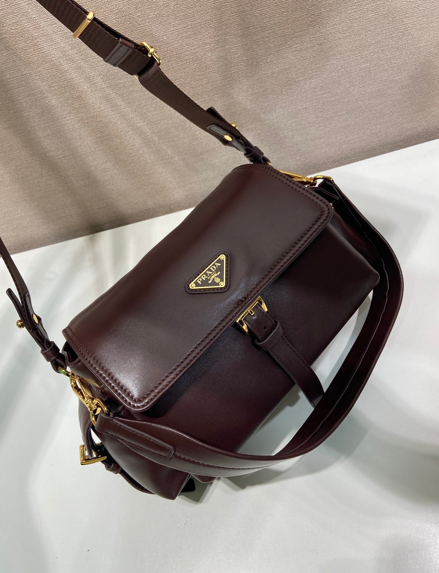 Prada leather crossbody bag with front flap and chain strap, dark brown.
