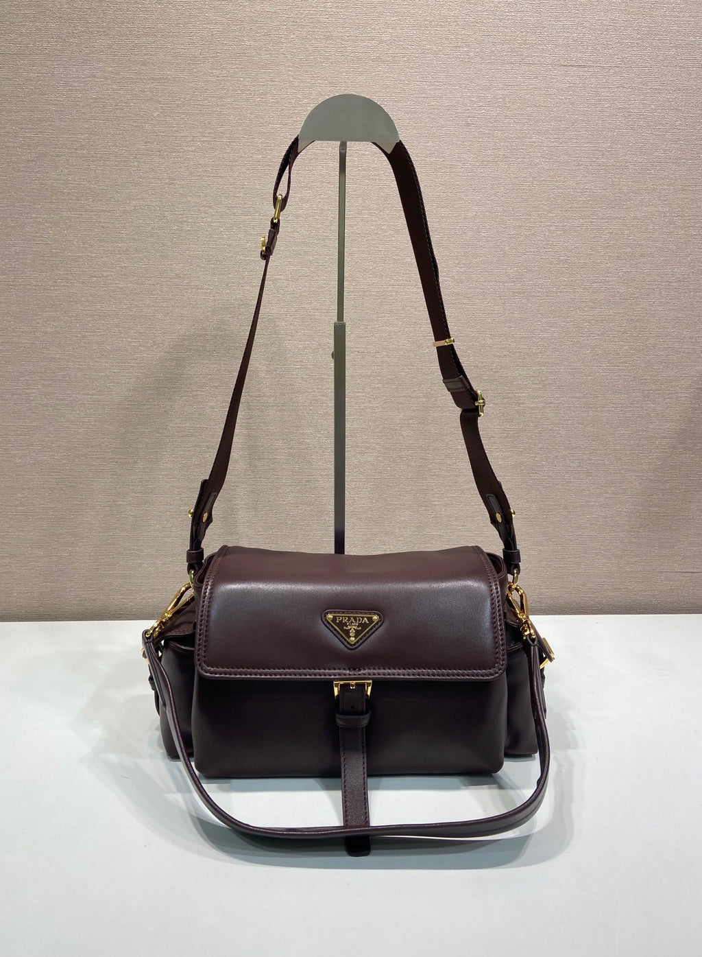 Prada leather shoulder bag with flap and gold-tone hardware, dark brown.