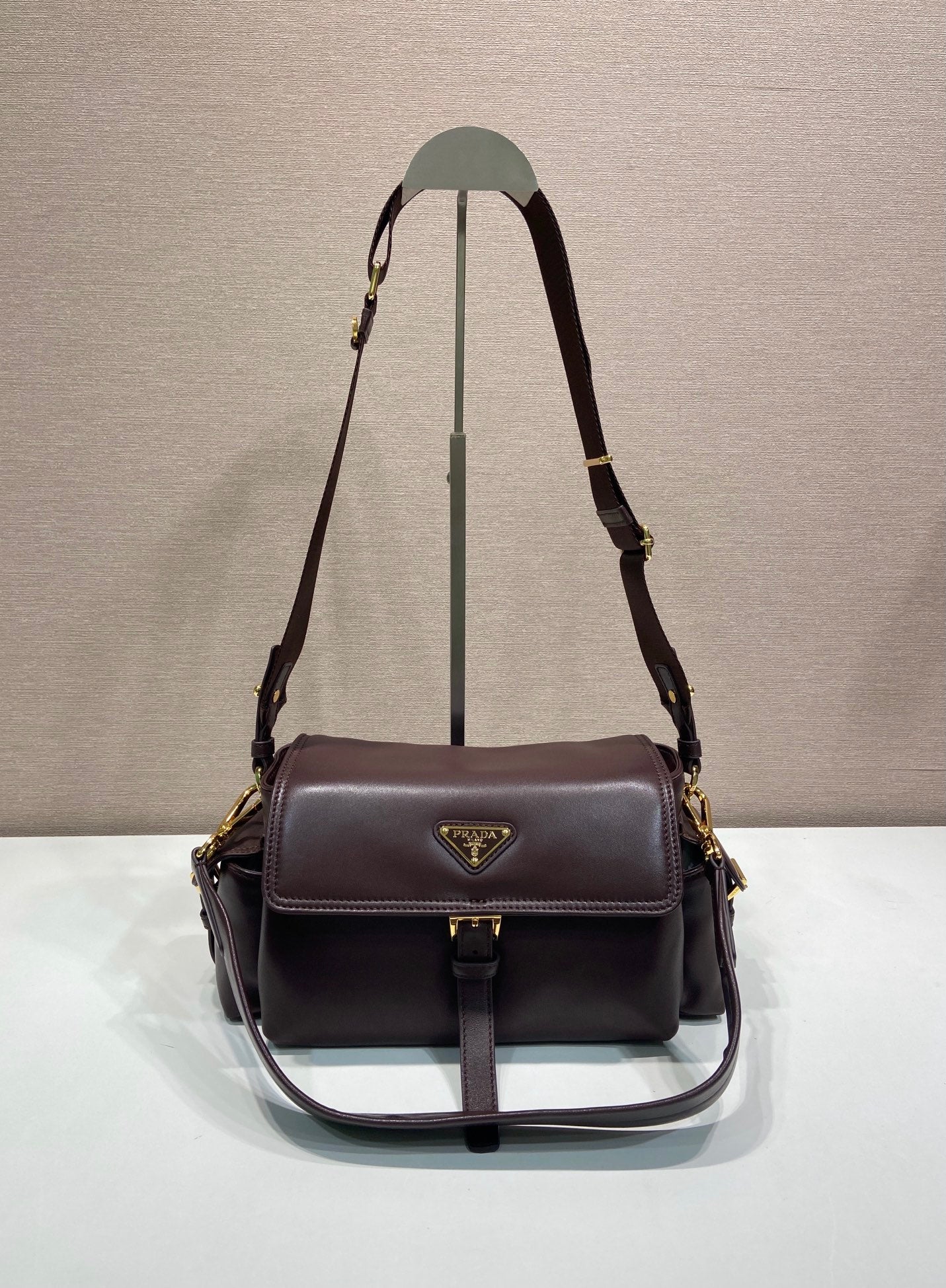 Prada leather shoulder bag with flap and gold-tone hardware, dark brown.