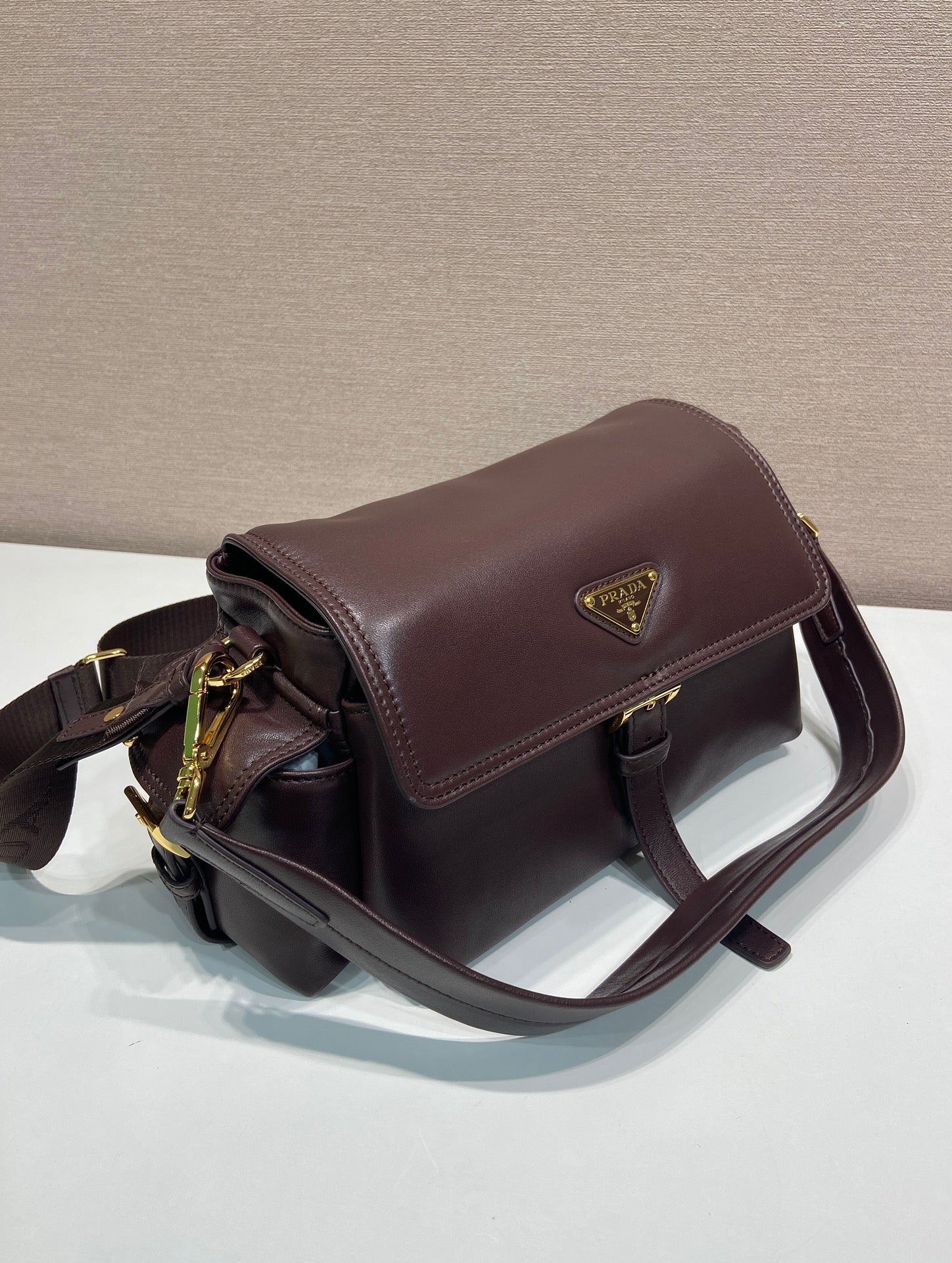 Prada leather shoulder bag with structured top flap, dark brown.