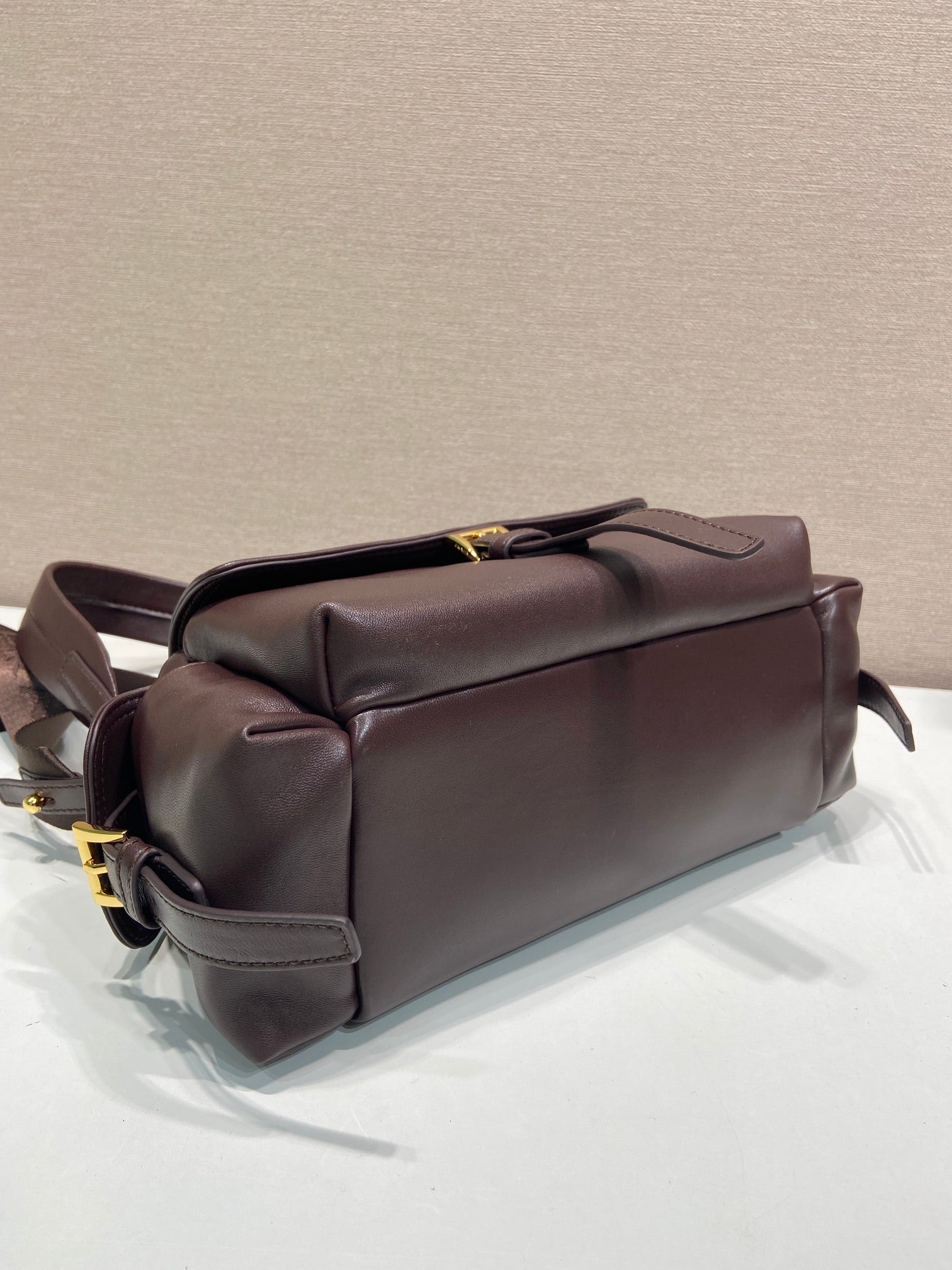 Prada leather bag with top handle and side straps, dark brown.