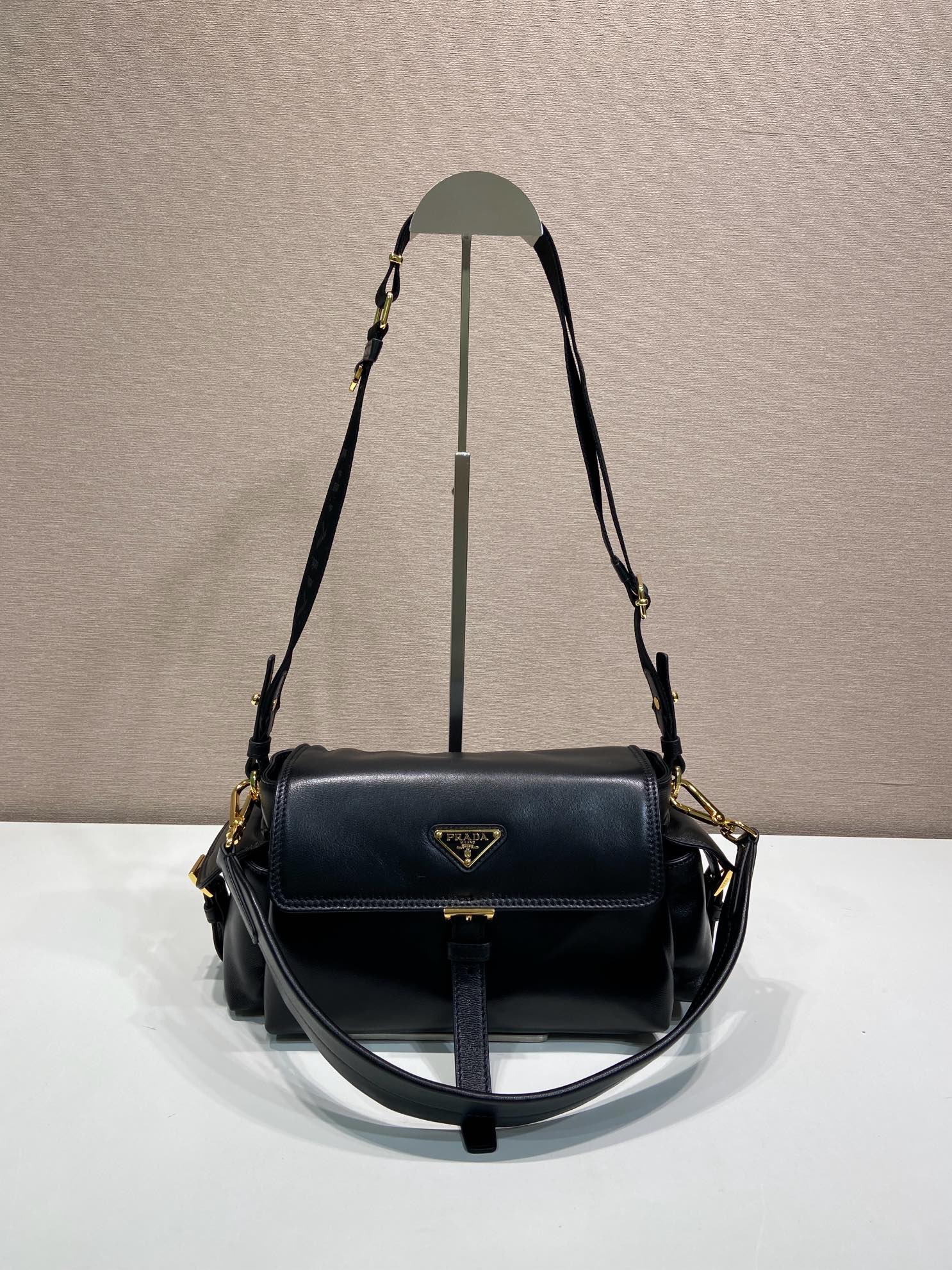 Prada black leather shoulder bag with flap, gold hardware, and adjustable strap.